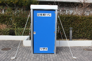 マンホールトイレが風で飛ばされないようの上屋の四隅をロープで固定している写真