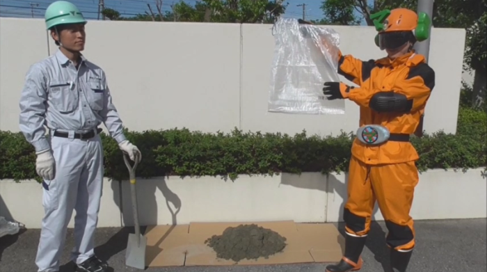 作業服を着た男性（左）がスコップを持ち、下水戦士マモルンダー（右）が透明な土嚢袋を持っている写真