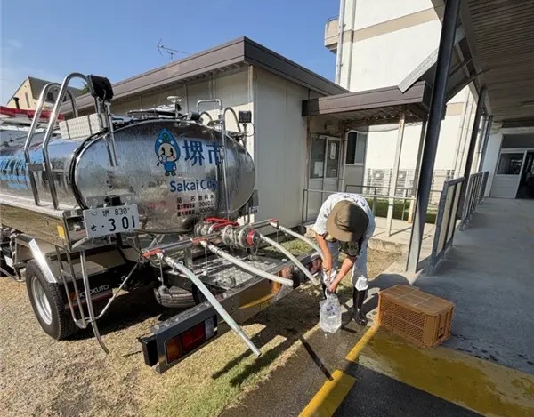 給水タンク車から給水袋へ水を入れている写真