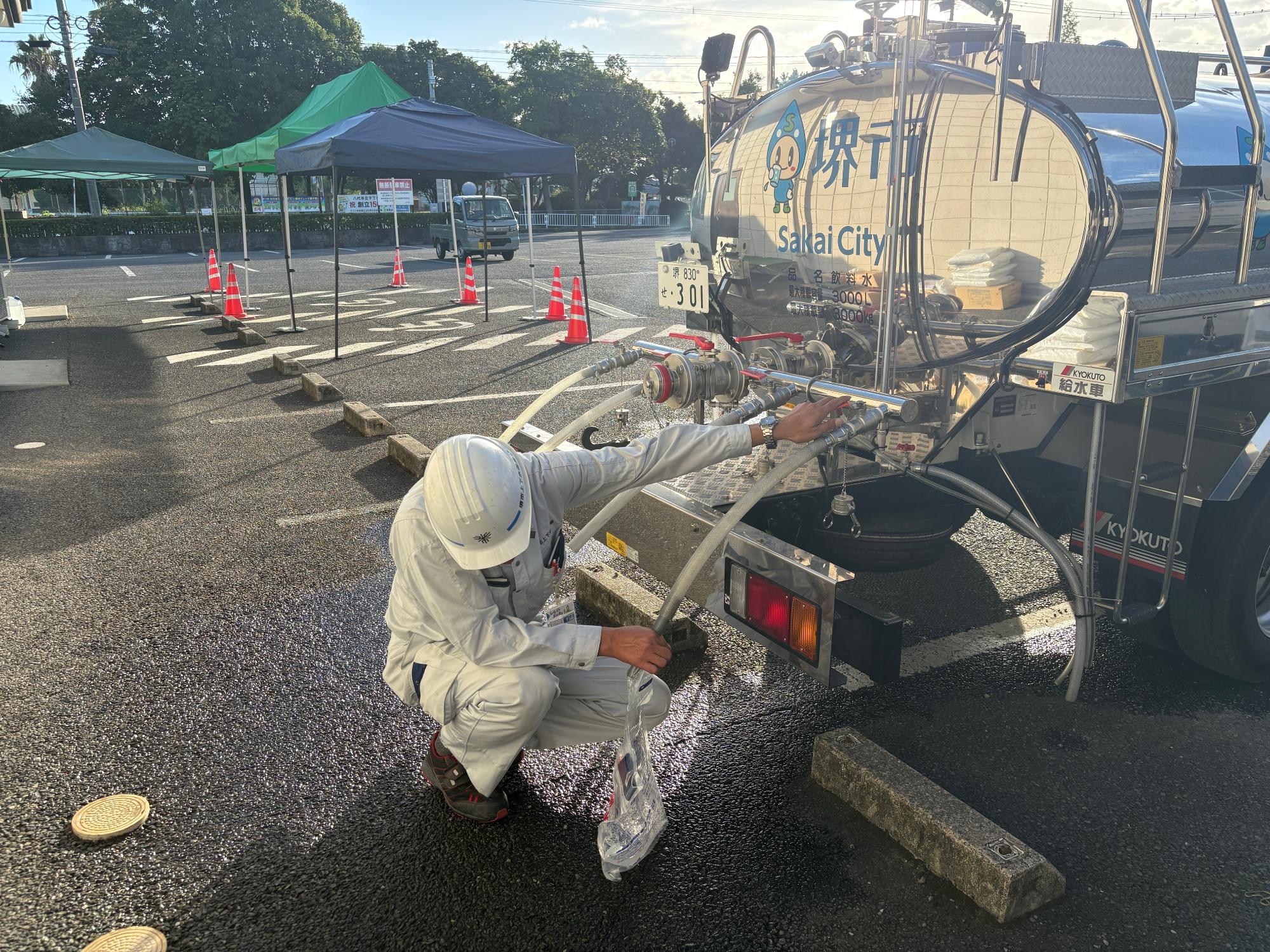 給水タンク車から給水袋へ水を入れている写真