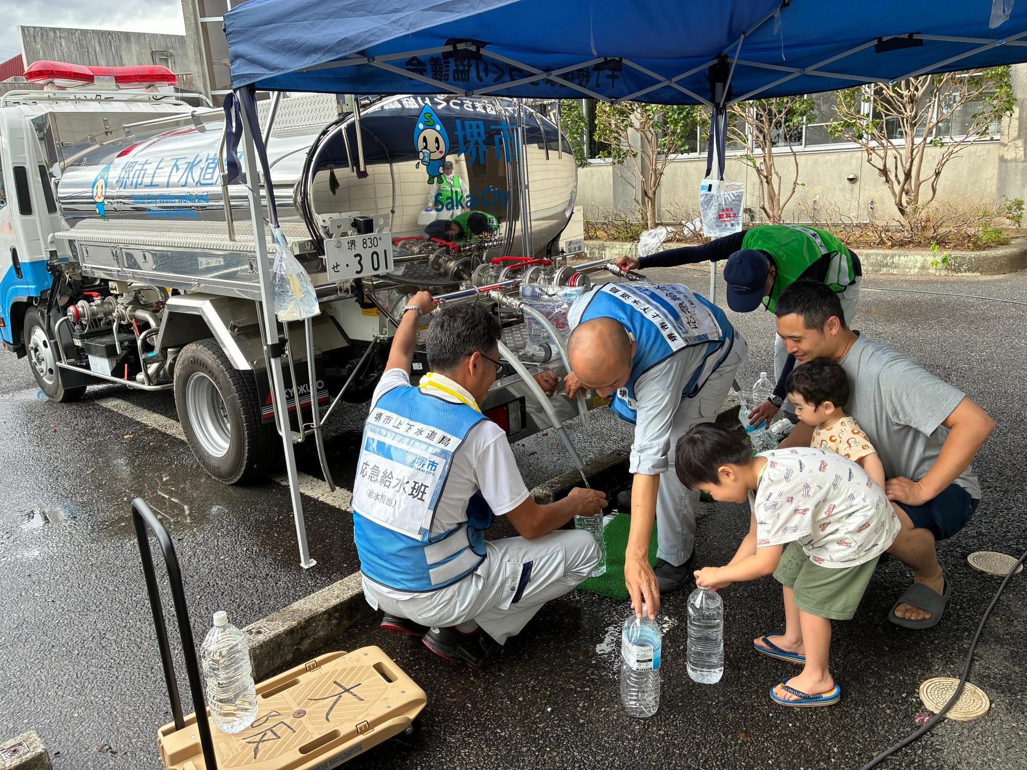 給水タンク車からペットボトルへ水を入れている写真