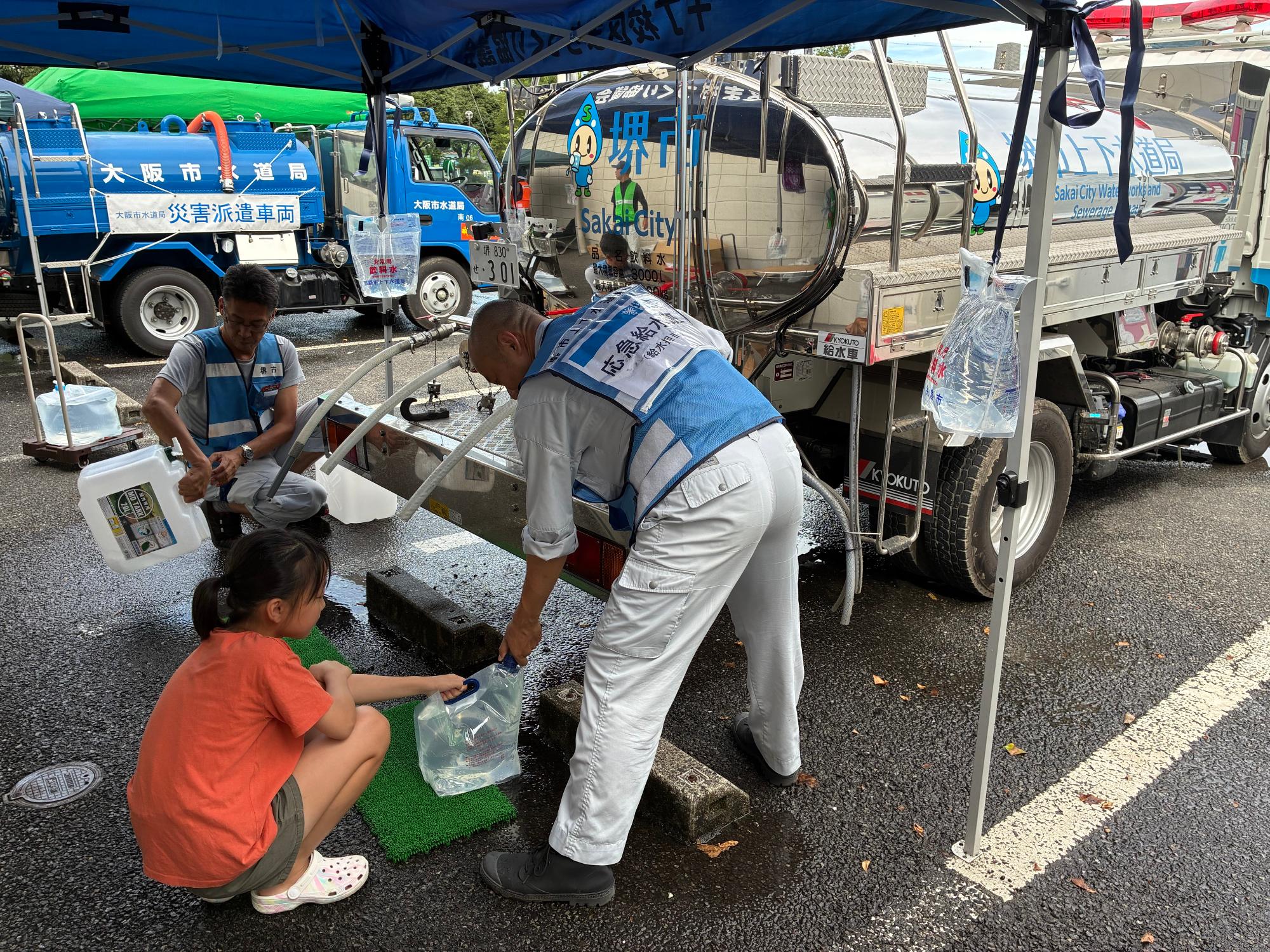 給水タンク車から給水袋へ水を入れている写真