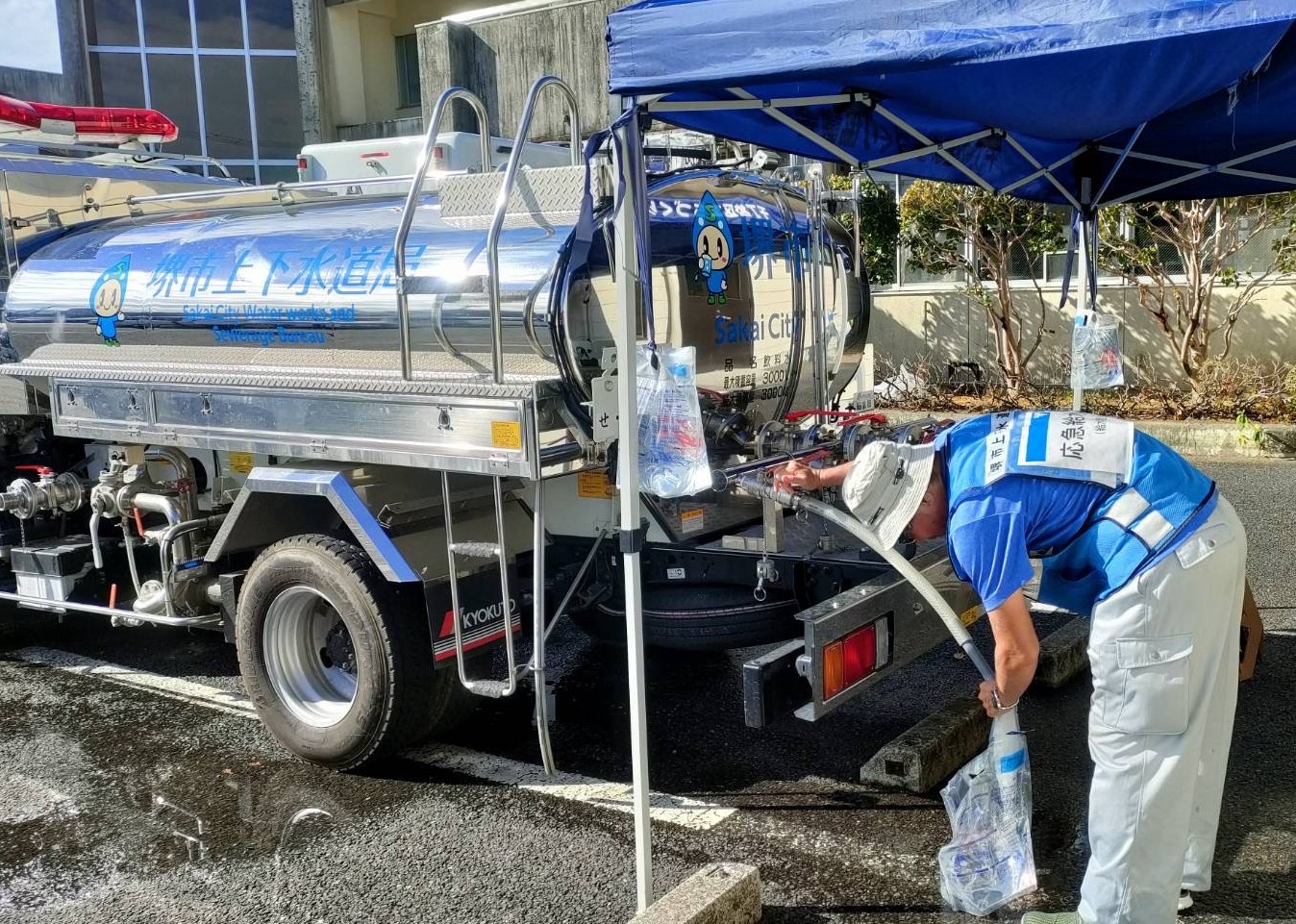 給水タンク車から給水袋へ水を入れている写真
