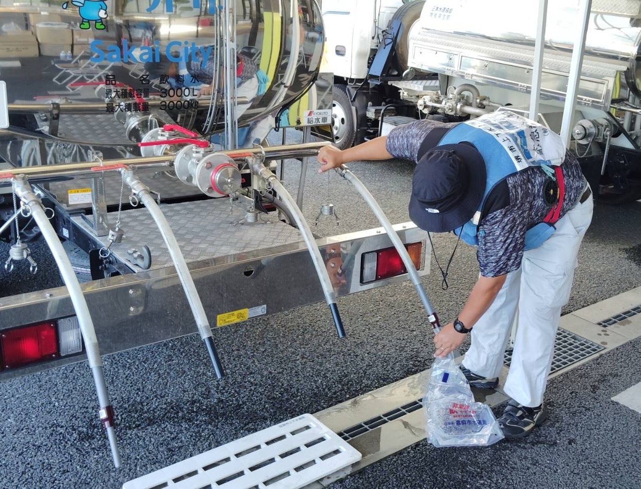 給水タンク車から給水袋へ水を入れている写真