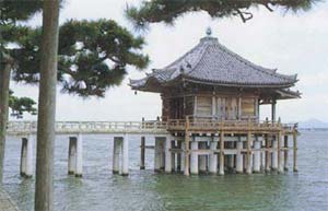 琵琶湖の上に橋が作られ、橋の先端に瓦屋根の建物が建っている写真