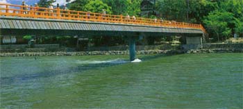手すりが朱色の朝霧橋が宇治川に建てられている写真