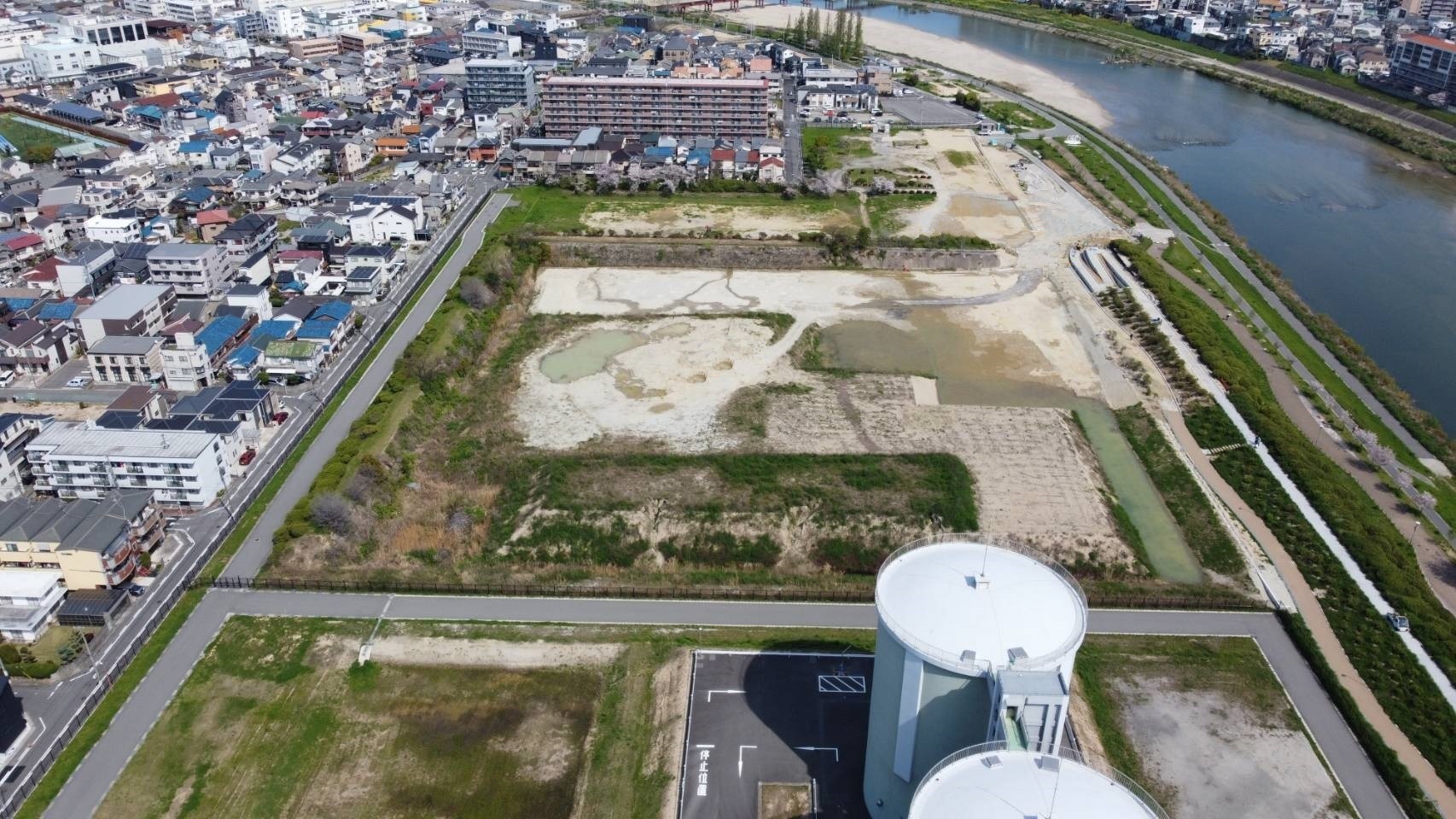 手前にタンクが2基あり奥が更地になっている浅香山浄水場跡地を上空から写した写真