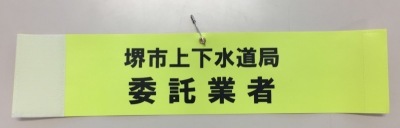 「堺市上下水道局委託業者」と書かれている黄色の腕章の写真